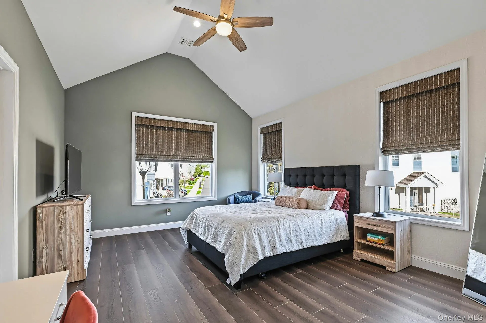 Vaulted ceiling with a central wood-finish ceiling fan, wood-finish flooring, and expansive windows Vaulted ceiling with a central wood-finish ceiling fan, wood-finish flooring, and expansive windows