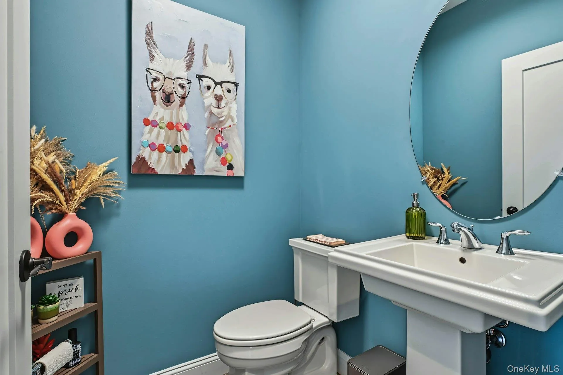 Powder room featuring a white pedestal sink, chrome widespread faucet, and circular wall-mounted mirror Powder room featuring a white pedestal sink, chrome widespread faucet, and circular wall-mounted mirror