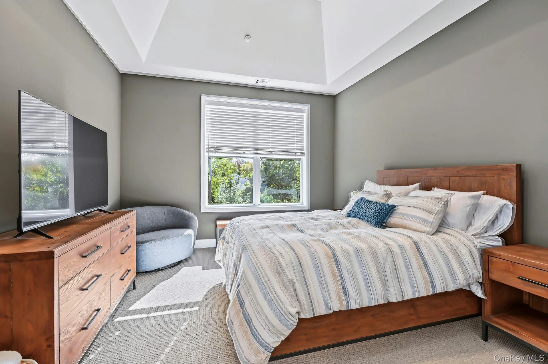 Vaulted ceiling featuring a central light fixture, neutral wall palette, and expansive window with horizontal blinds Vaulted ceiling featuring a central light fixture, neutral wall palette, and expansive window with horizontal blinds