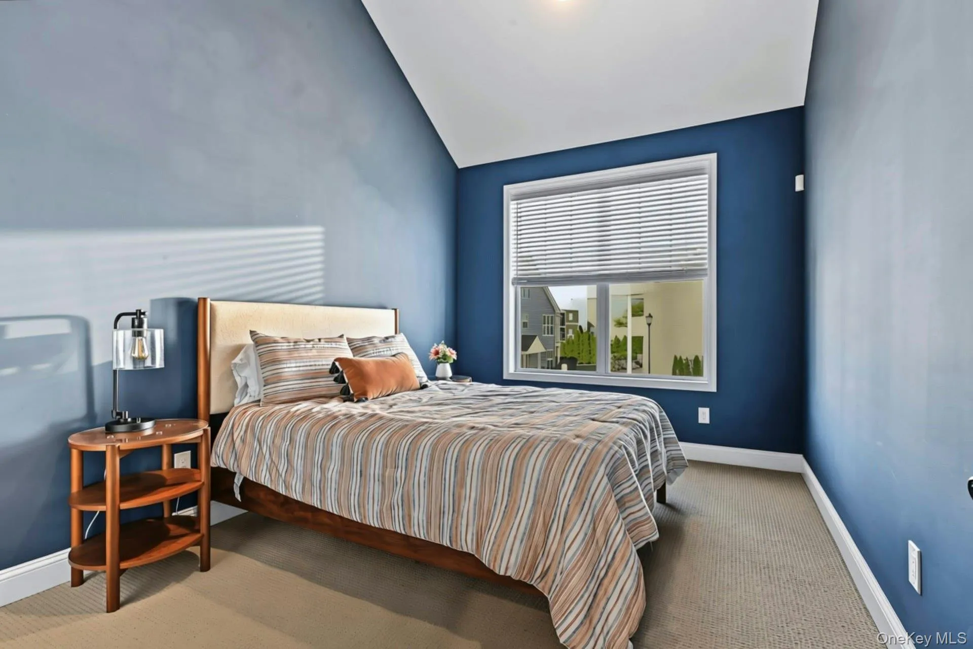 Vaulted ceilings, neutral carpeting, and a large window with horizontal blinds Vaulted ceilings, neutral carpeting, and a large window with horizontal blinds