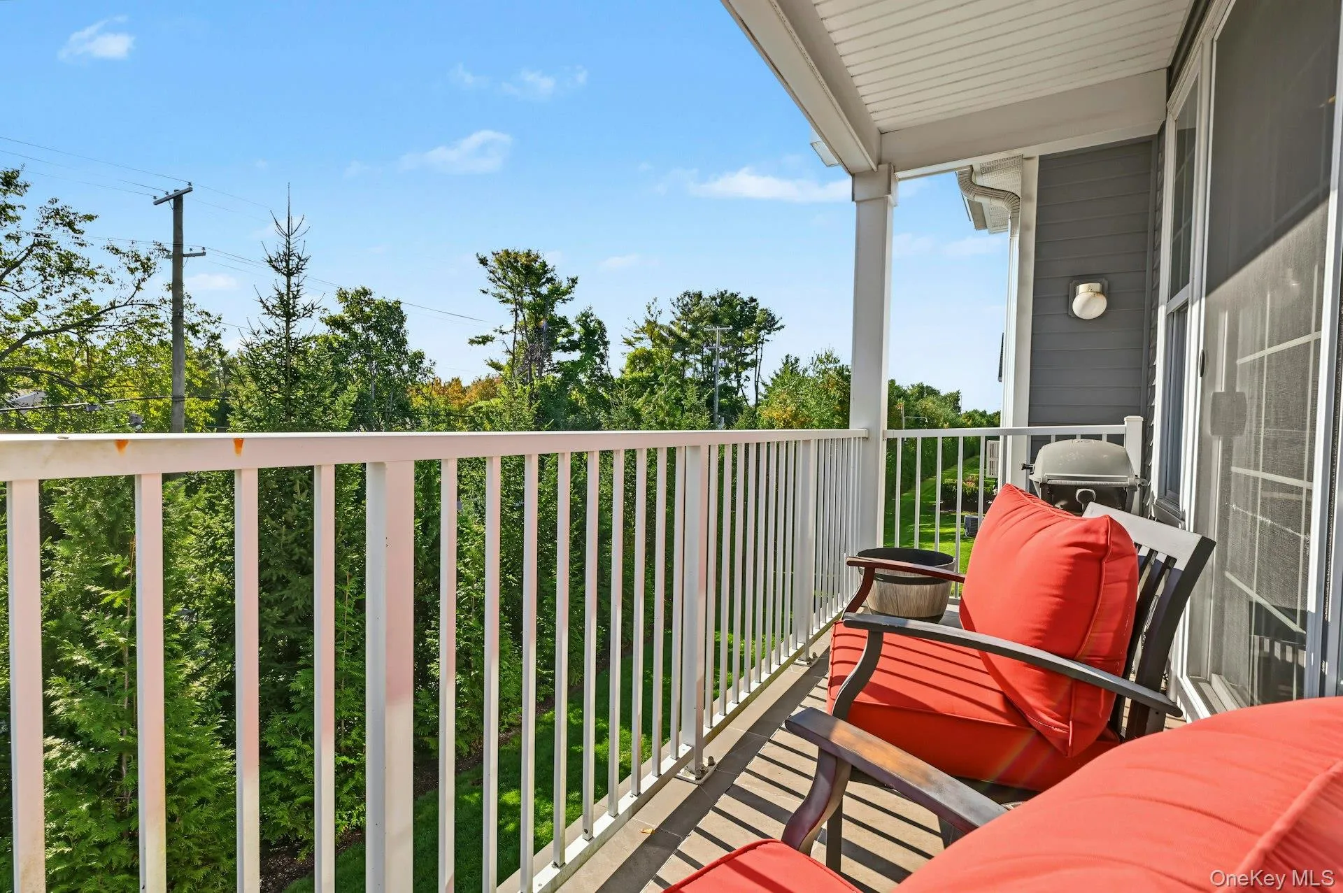 Covered balcony featuring white metal railings, vertical siding, and exterior wall-mounted lighting Covered balcony featuring white metal railings, vertical siding, and exterior wall-mounted lighting