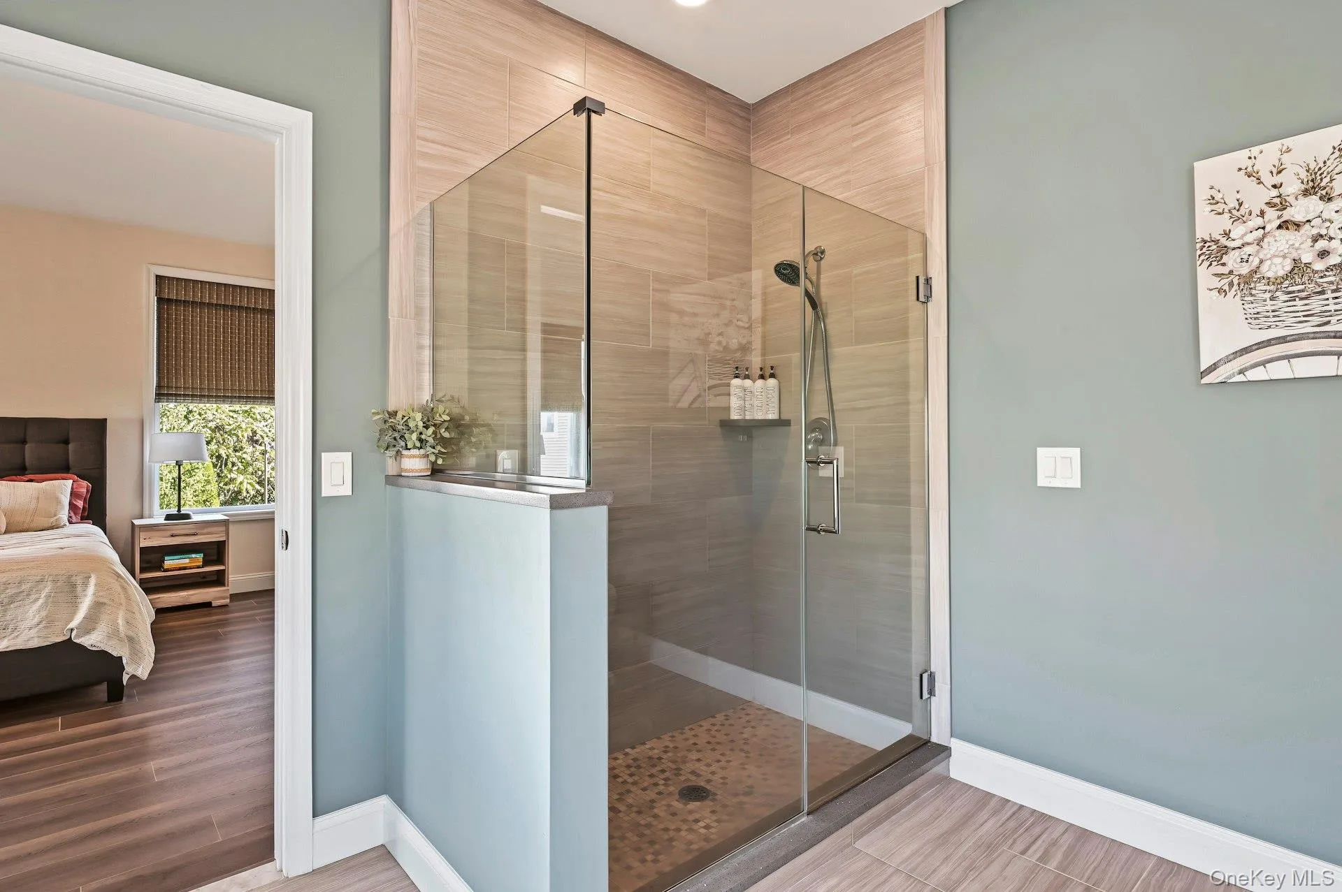 Shower featuring a glass enclosure, floor-to-ceiling tile surround, pebble-style stone floor, and handheld shower fixture Shower featuring a glass enclosure, floor-to-ceiling tile surround, pebble-style stone floor, and handheld shower fixture