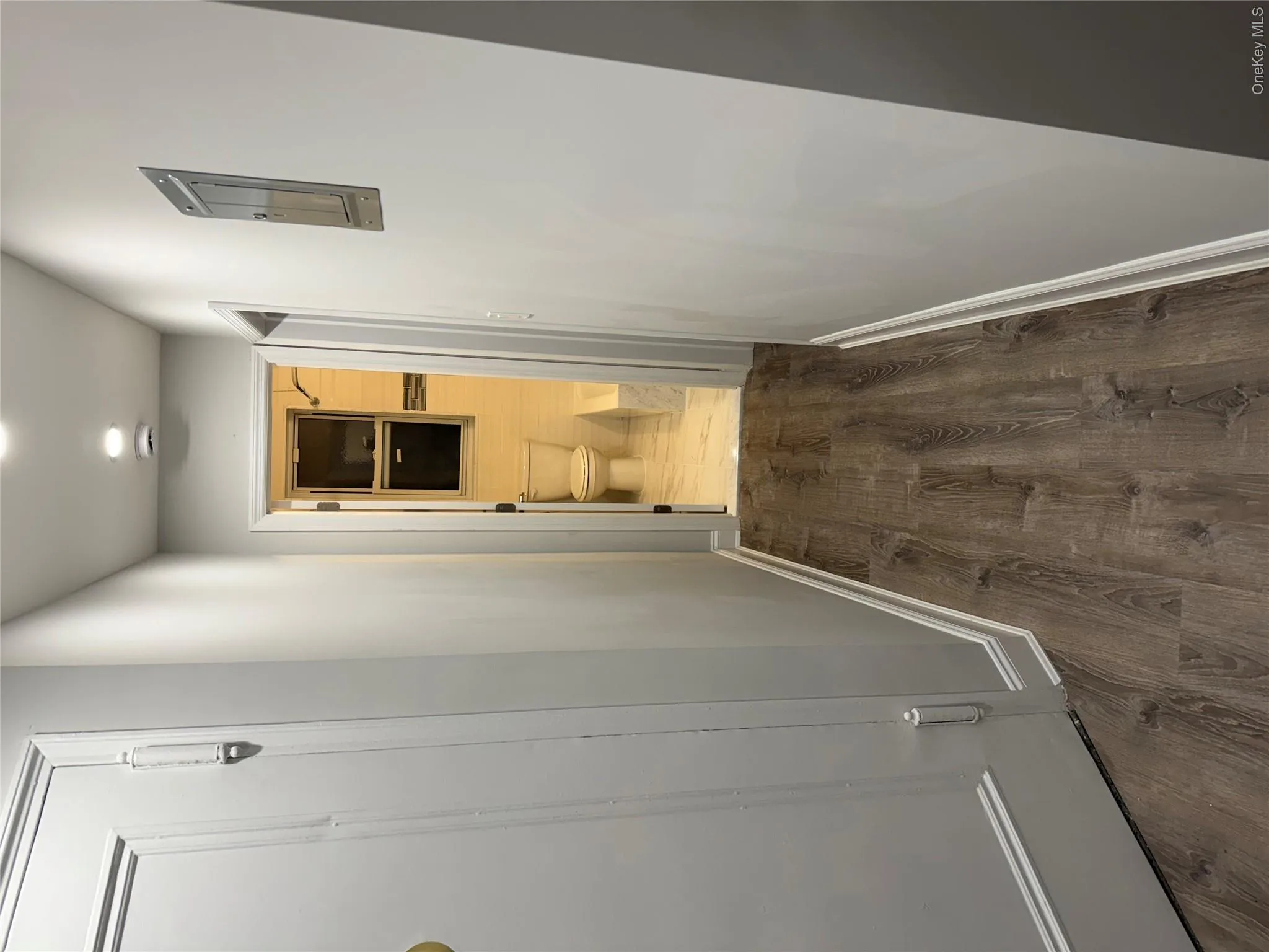 Hallway featuring wood-finish flooring, recessed lighting, and white door frames Hallway featuring wood-finish flooring, recessed lighting, and white door frames