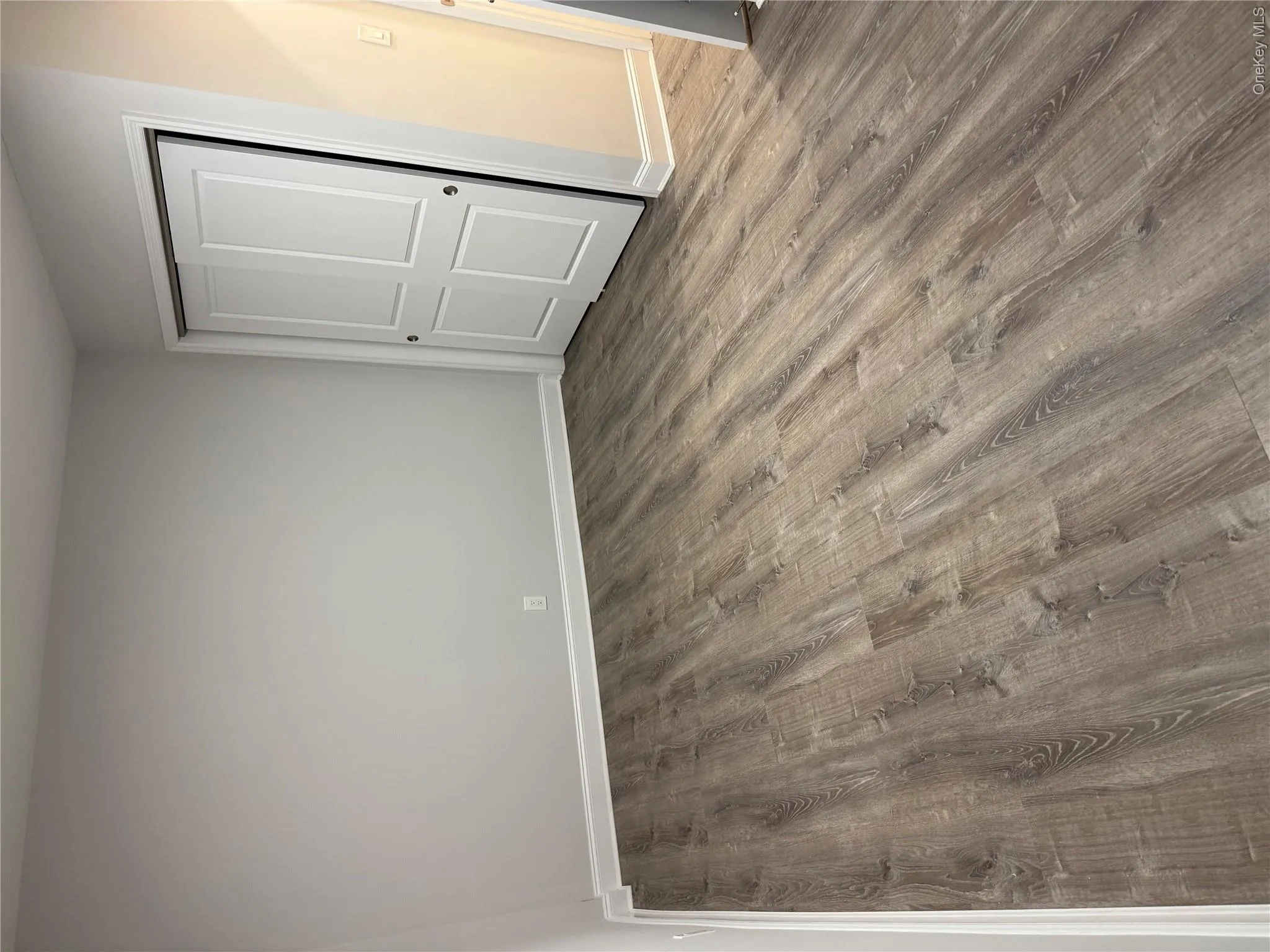 Neutral wall tones, wood-finish flooring, and white two-panel sliding closet doors Neutral wall tones, wood-finish flooring, and white two-panel sliding closet doors