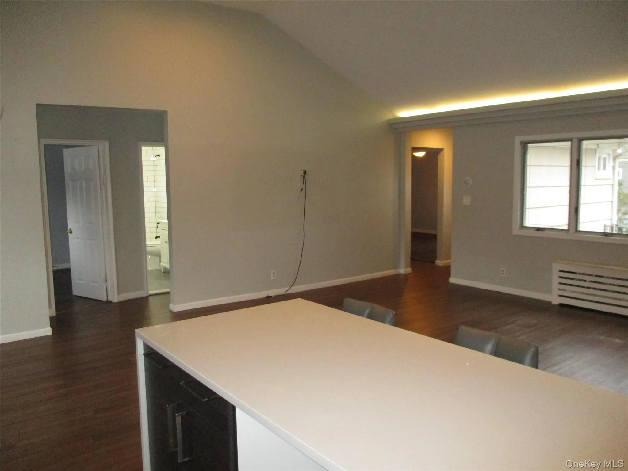 Kitchen with dark wood finished floors, vaulted ceiling, light countertops, and radiator heating unit Kitchen with dark wood finished floors, vaulted ceiling, light countertops, and radiator heating unit