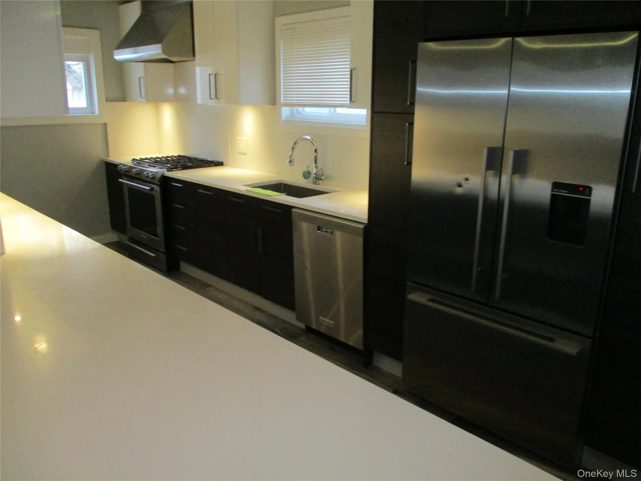 Kitchen featuring stainless steel appliances, extractor fan, dark cabinetry, and white cabinetry Kitchen featuring stainless steel appliances, extractor fan, dark cabinetry, and white cabinetry