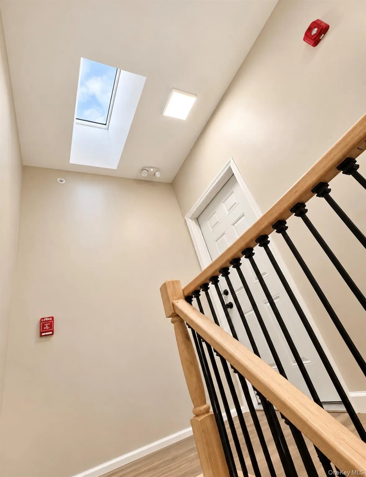 Skylight providing natural illumination, wood-finish handrail, and black metal balusters Skylight providing natural illumination, wood-finish handrail, and black metal balusters