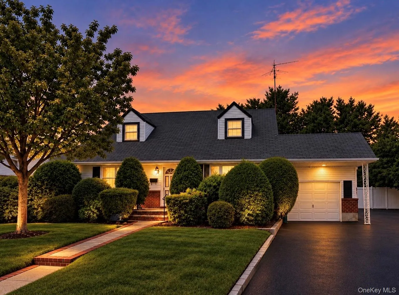 Cape Cod-style residence in twilight featuring dormer brick masonry accents, a paved walkway, and an attached single-car garage Cape Cod-style residence in twilight featuring dormer brick masonry accents, a paved walkway, and an attached single-car garage