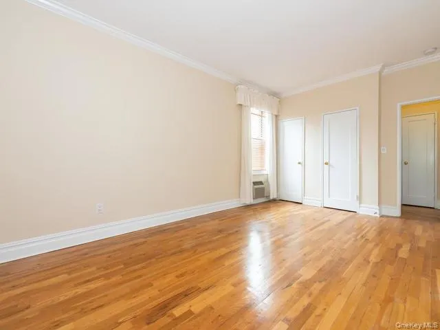 Interior room featuring wood-finish flooring, crown molding, and white panel doors Interior room featuring wood-finish flooring, crown molding, and white panel doors