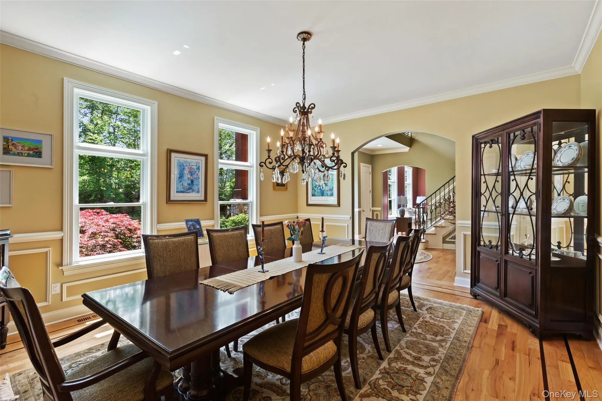 Dining space with arched walkways, light wood finished floors, crown molding, stairway, and wainscoting Dining space with arched walkways, light wood finished floors, crown molding, stairway, and wainscoting