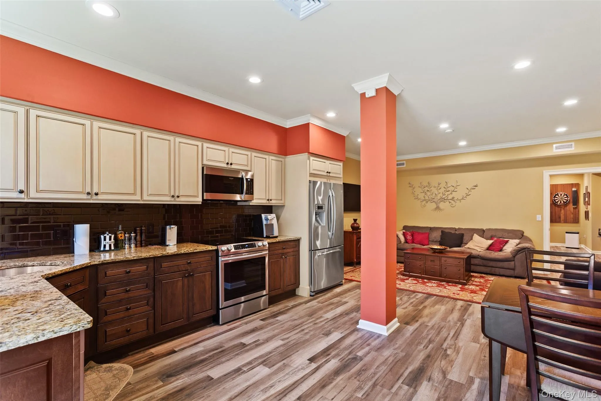 Kitchen with appliances with stainless steel finishes, cream cabinets, open floor plan, tasteful backsplash, and light stone countertops Kitchen with appliances with stainless steel finishes, cream cabinets, open floor plan, tasteful backsplash, and light stone countertops