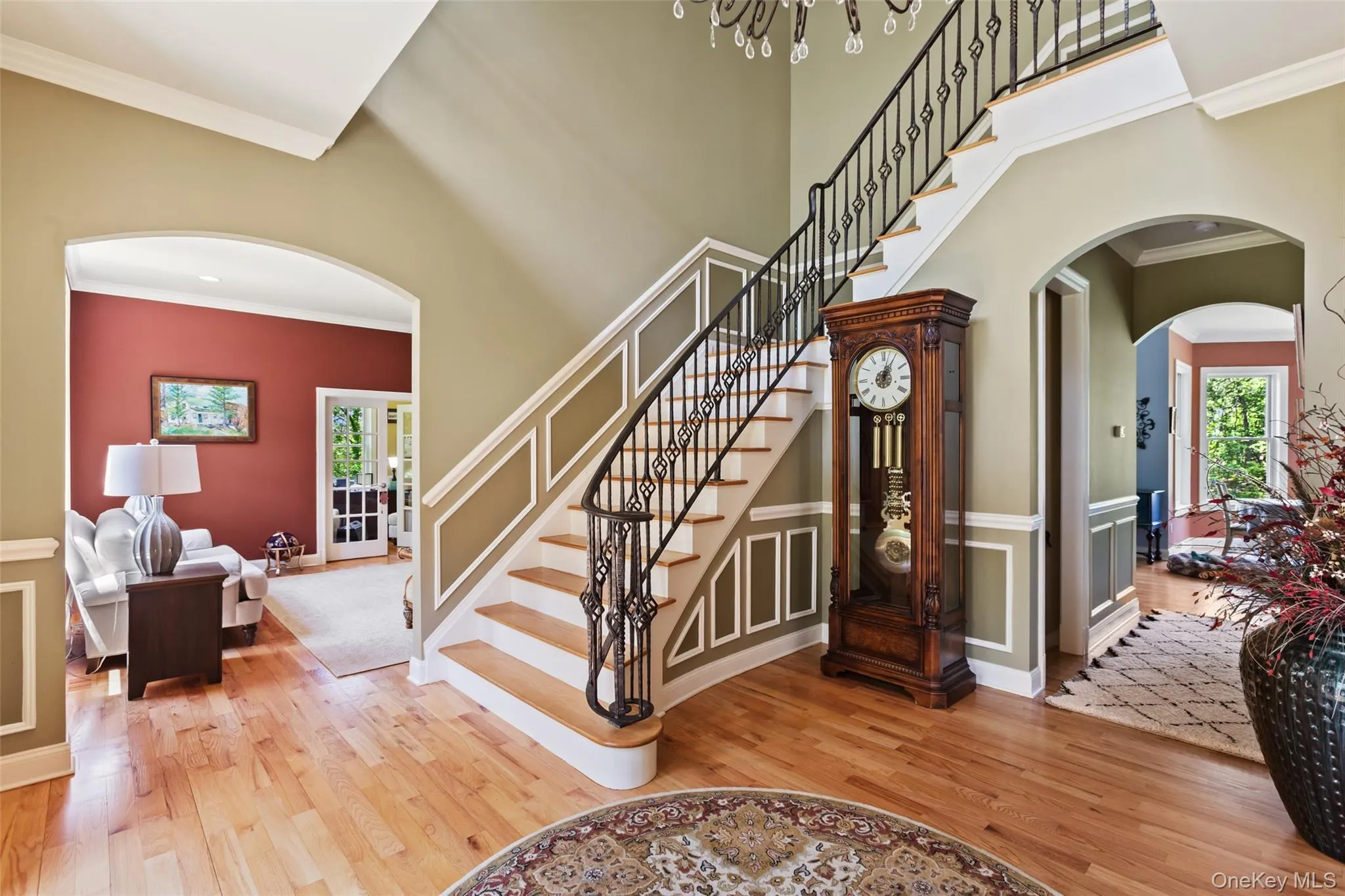 Stairway with wood finished floors, healthy amount of natural light, arched walkways, ornamental molding, and a towering ceiling Stairway with wood finished floors, healthy amount of natural light, arched walkways, ornamental molding, and a towering ceiling