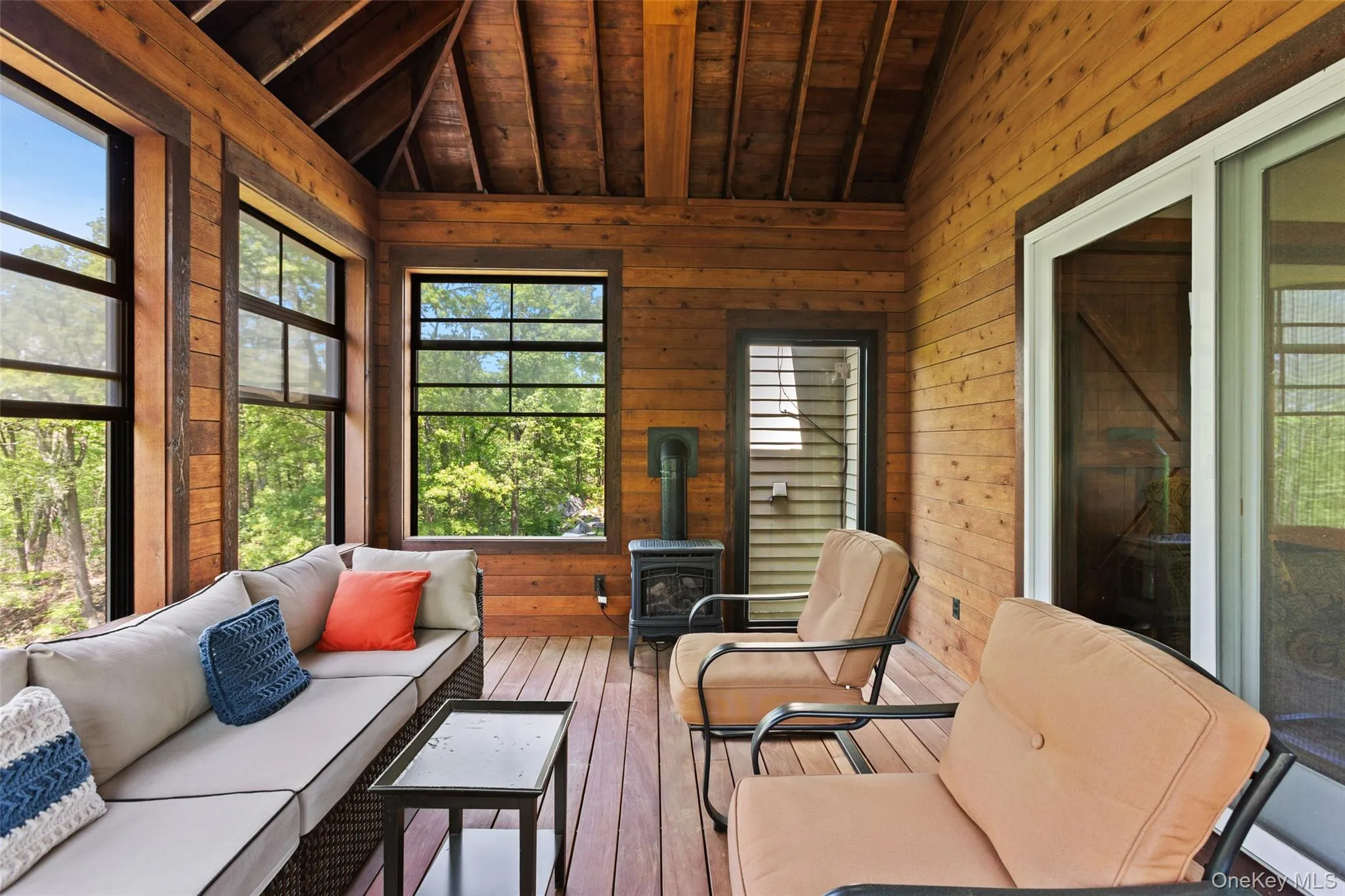 Sunroom / solarium with wood ceiling, wooden walls, a wood stove, and hardwood / wood-style floors Sunroom / solarium with wood ceiling, wooden walls, a wood stove, and hardwood / wood-style floors