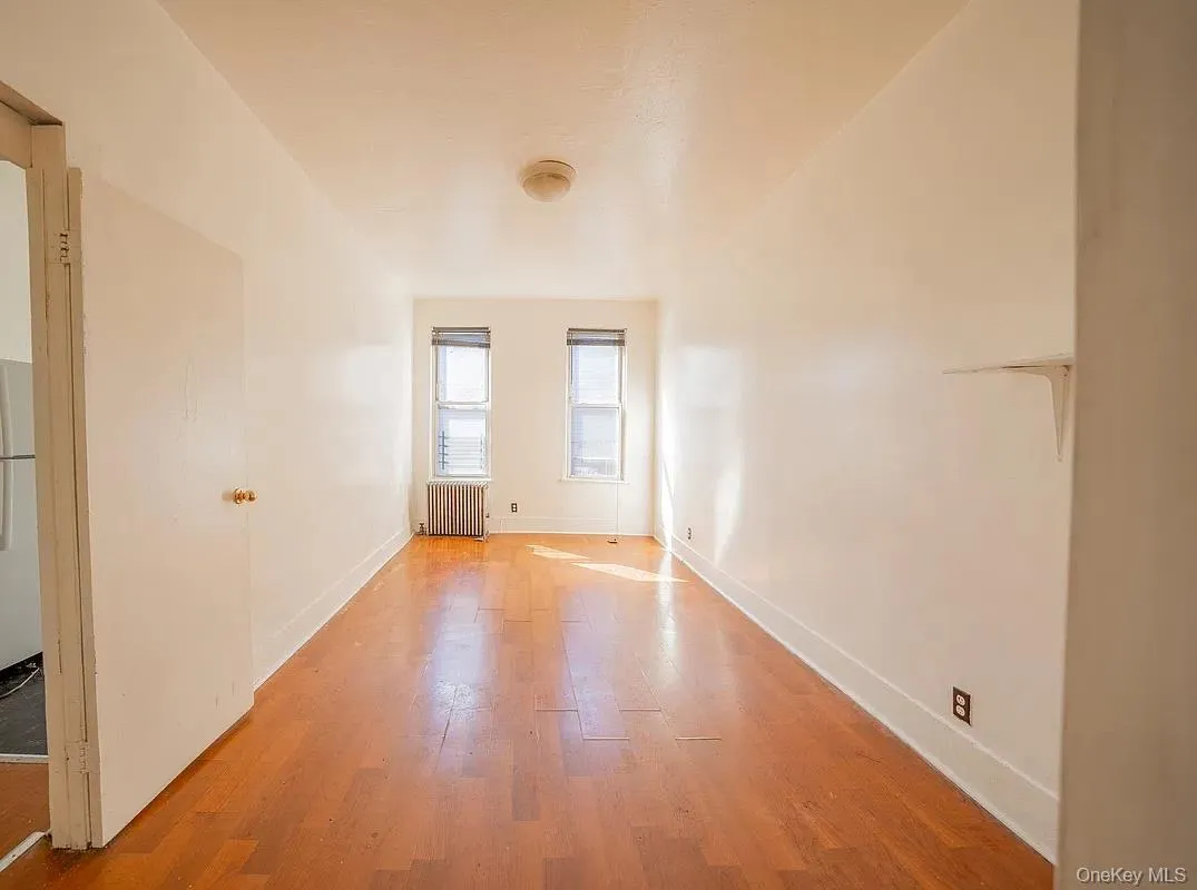 Interior space featuring wood-finish flooring, two double-hung windows and a metallic radiator. Interior space featuring wood-finish flooring, two double-hung windows and a metallic radiator.