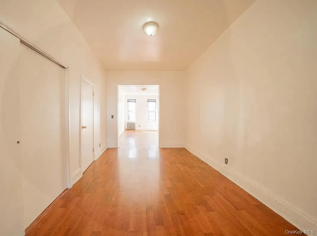 Interior space featuring wood-finish flooring, white walls, flush-mount overhead lighting, and sliding closet doors. Interior space featuring wood-finish flooring, white walls, flush-mount overhead lighting, and sliding closet doors.