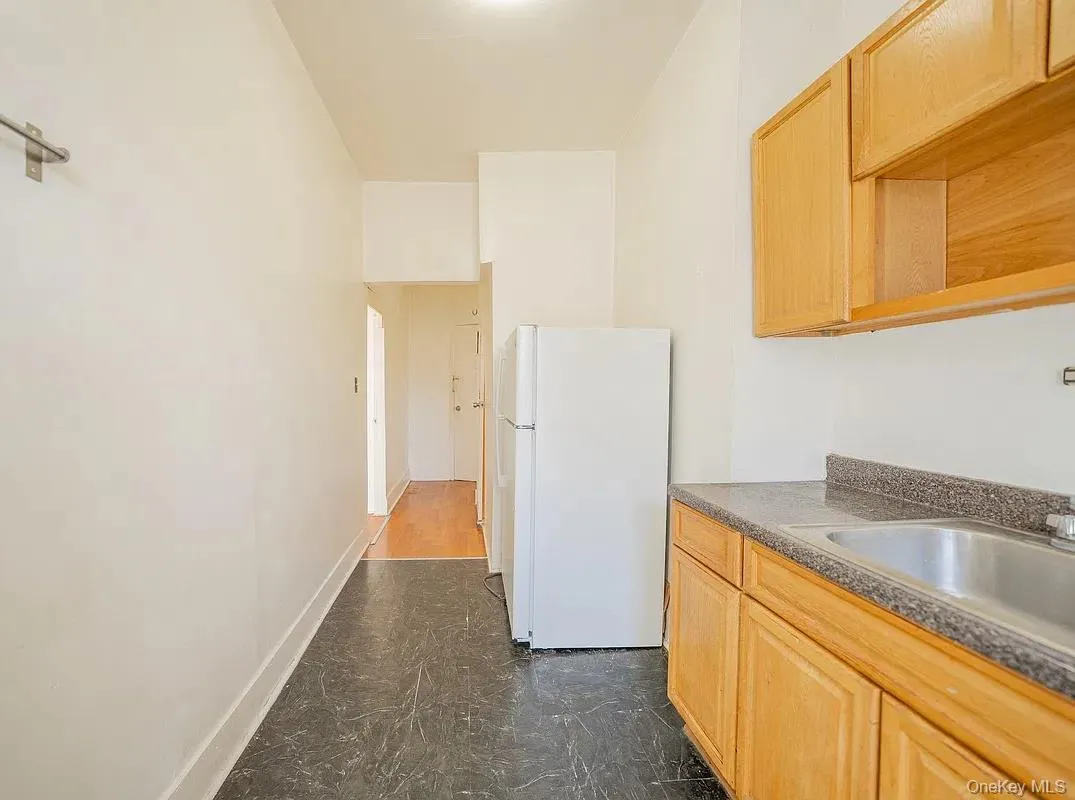 Kitchen featuring natural wood-finish cabinetry, solid-surface countertops, a stainless steel sink, and durable dark flooring. Kitchen featuring natural wood-finish cabinetry, solid-surface countertops, a stainless steel sink, and durable dark flooring.