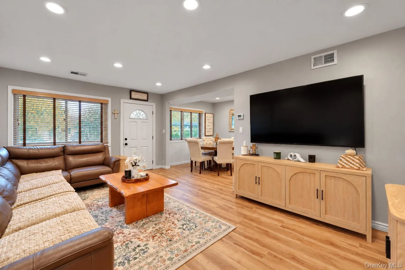 Open-concept living space featuring wood-finish flooring, recessed lighting, and a neutral color palette Open-concept living space featuring wood-finish flooring, recessed lighting, and a neutral color palette