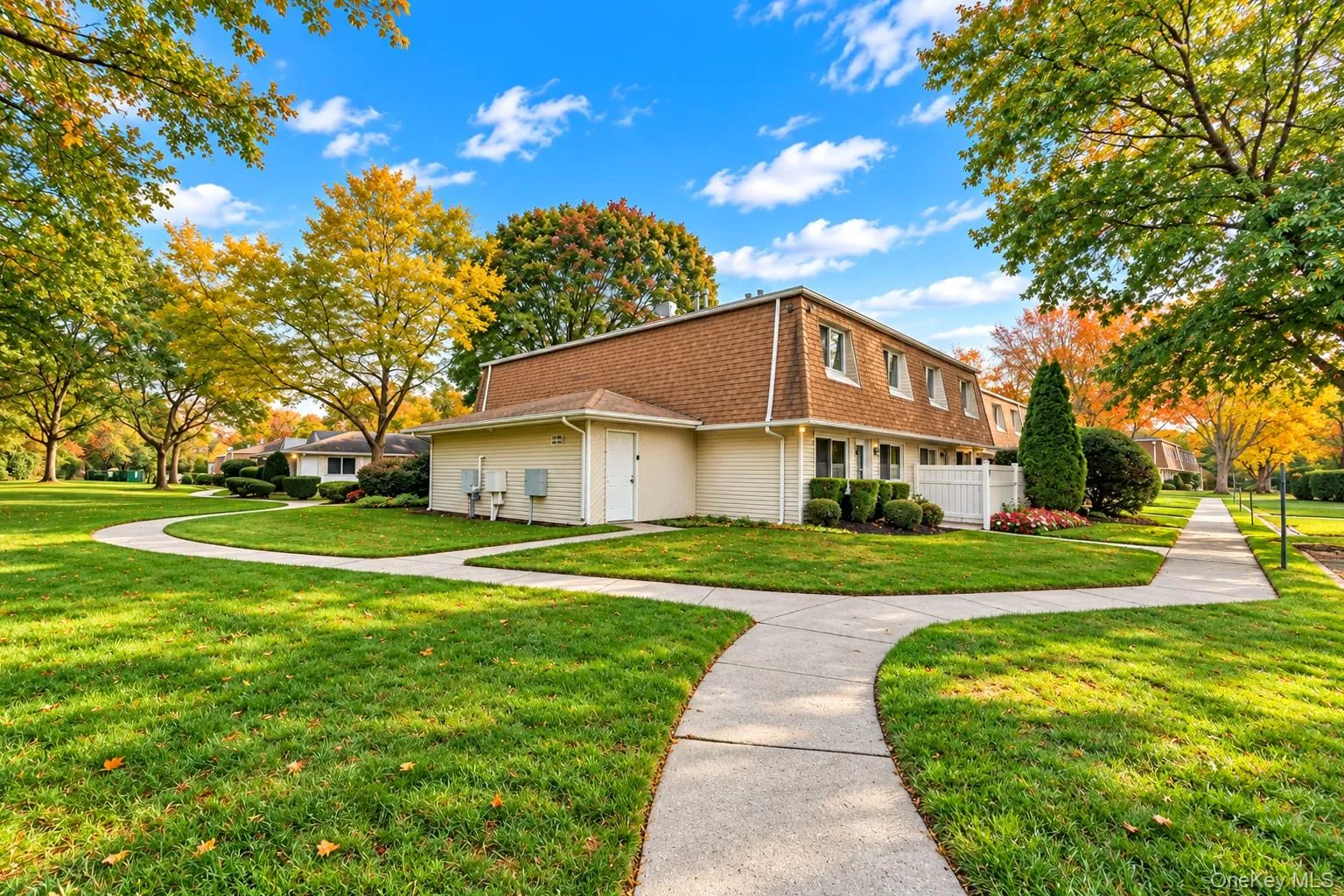 Multi-level exterior featuring tan brick siding, a mansard roof, expansive lawn, and concrete walkways Multi-level exterior featuring tan brick siding, a mansard roof, expansive lawn, and concrete walkways