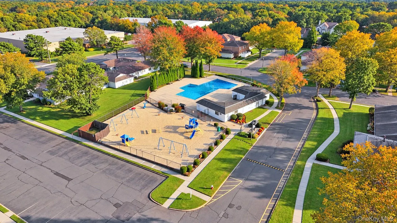 Outdoor swimming pool and playground area featuring a concrete deck, fenced enclosure, and a dedicated clubhouse structure Outdoor swimming pool and playground area featuring a concrete deck, fenced enclosure, and a dedicated clubhouse structure