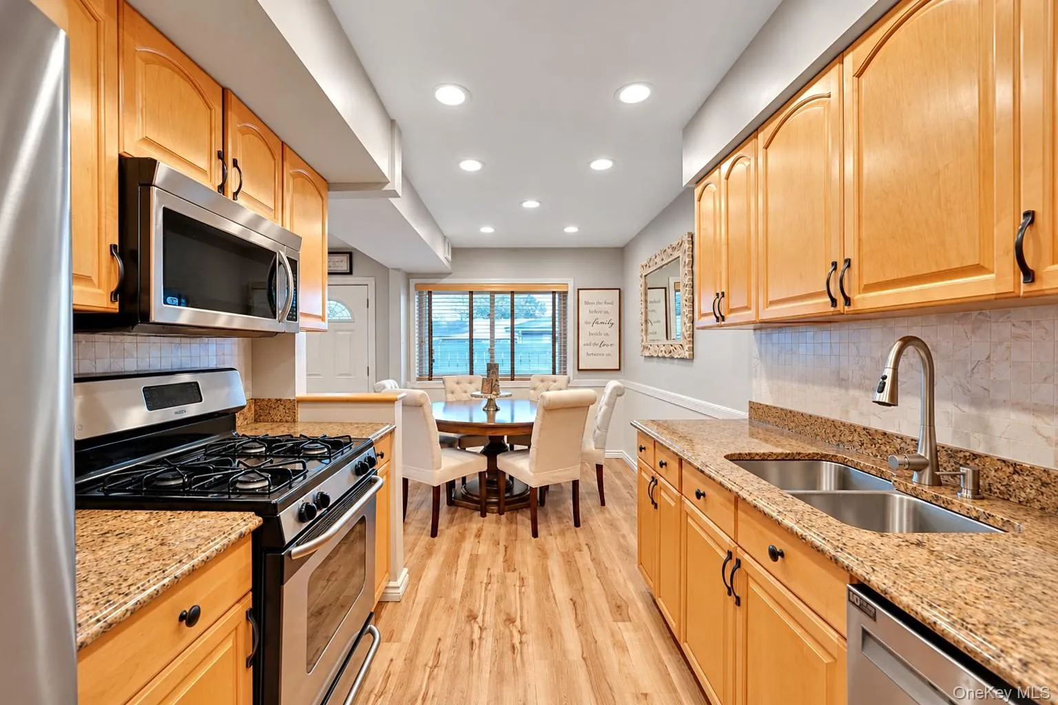 Galley kitchen featuring wood cabinetry, stone countertops, stainless steel appliances, wood-finish flooring, and recessed lighting Galley kitchen featuring wood cabinetry, stone countertops, stainless steel appliances, wood-finish flooring, and recessed lighting