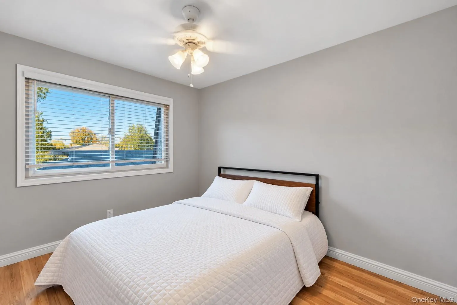Neutral-toned walls, wood-finish flooring, and a ceiling-mounted light fixture with an integrated fan Neutral-toned walls, wood-finish flooring, and a ceiling-mounted light fixture with an integrated fan