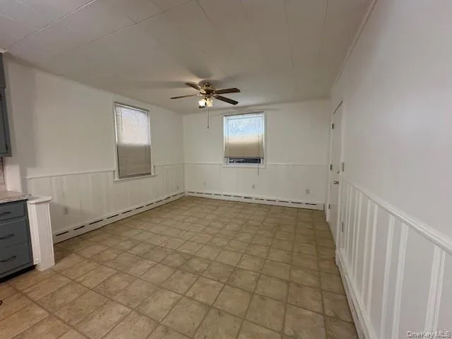 Spare room with wainscoting, a ceiling fan, and a baseboard radiator Spare room with wainscoting, a ceiling fan, and a baseboard radiator