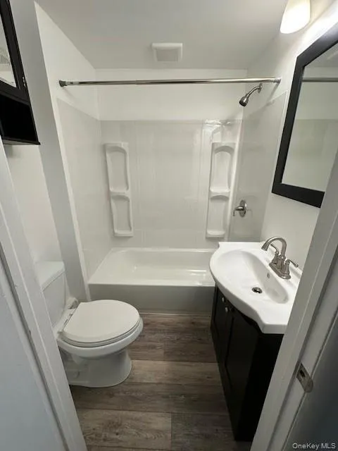 Full bathroom with vanity, dark wood finished floors, and shower combination Full bathroom with vanity, dark wood finished floors, and shower combination