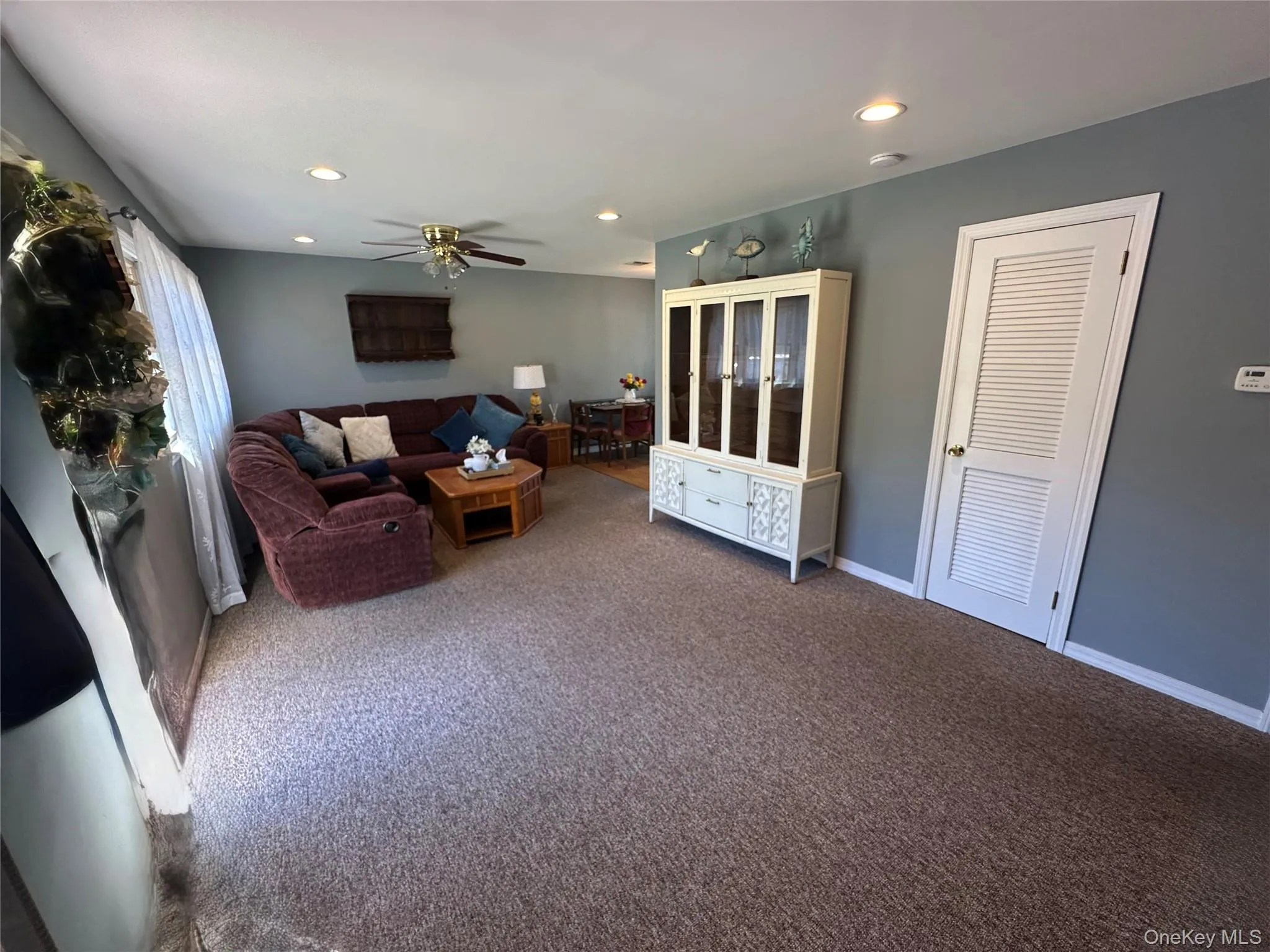 Living area featuring recessed lighting, a ceiling fan, neutral wall tones, and a paneled interior door Living area featuring recessed lighting, a ceiling fan, neutral wall tones, and a paneled interior door