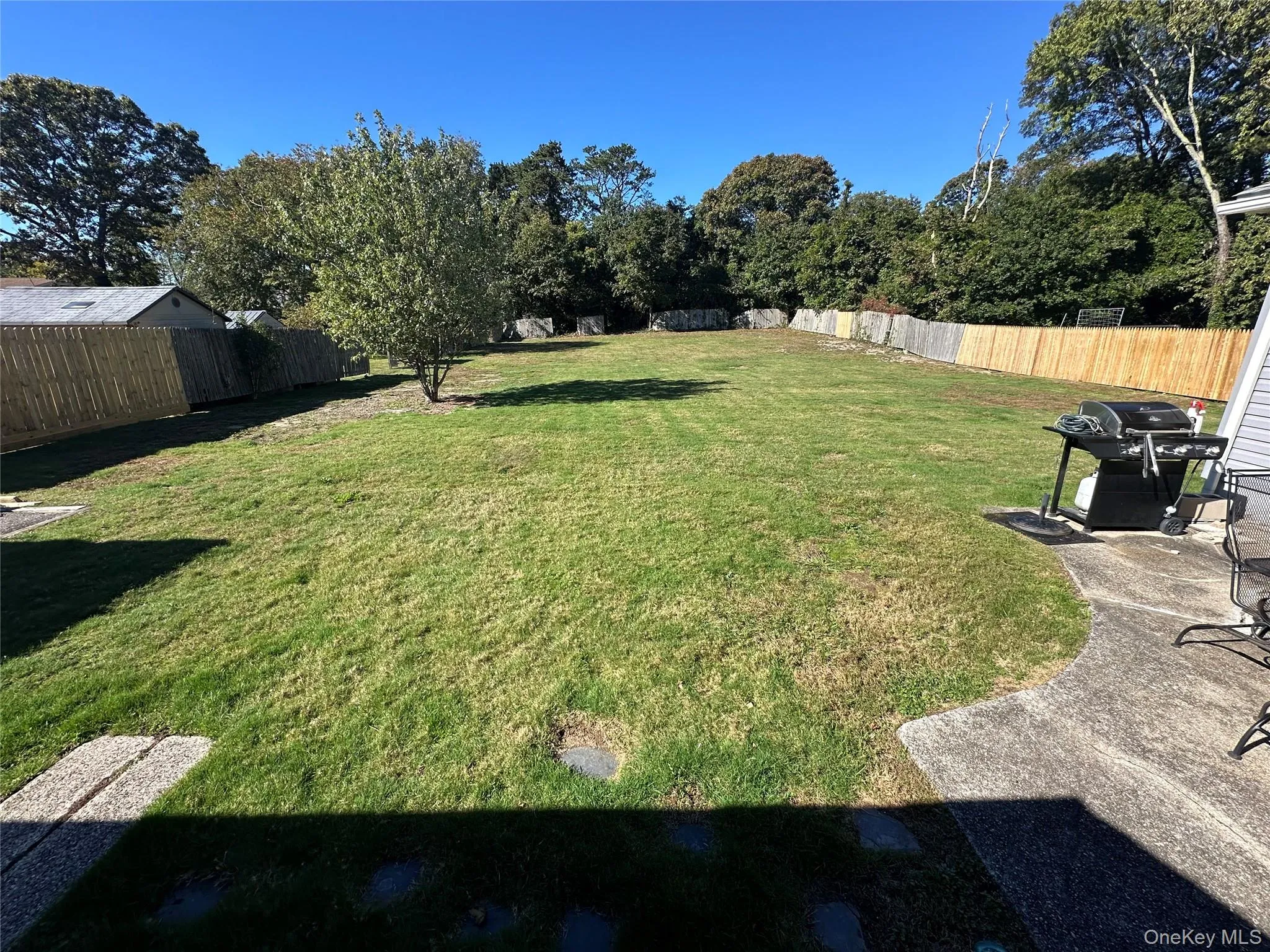 Expansive backyard featuring a large grass lawn, perimeter wooden privacy fencing, and mature trees Expansive backyard featuring a large grass lawn, perimeter wooden privacy fencing, and mature trees