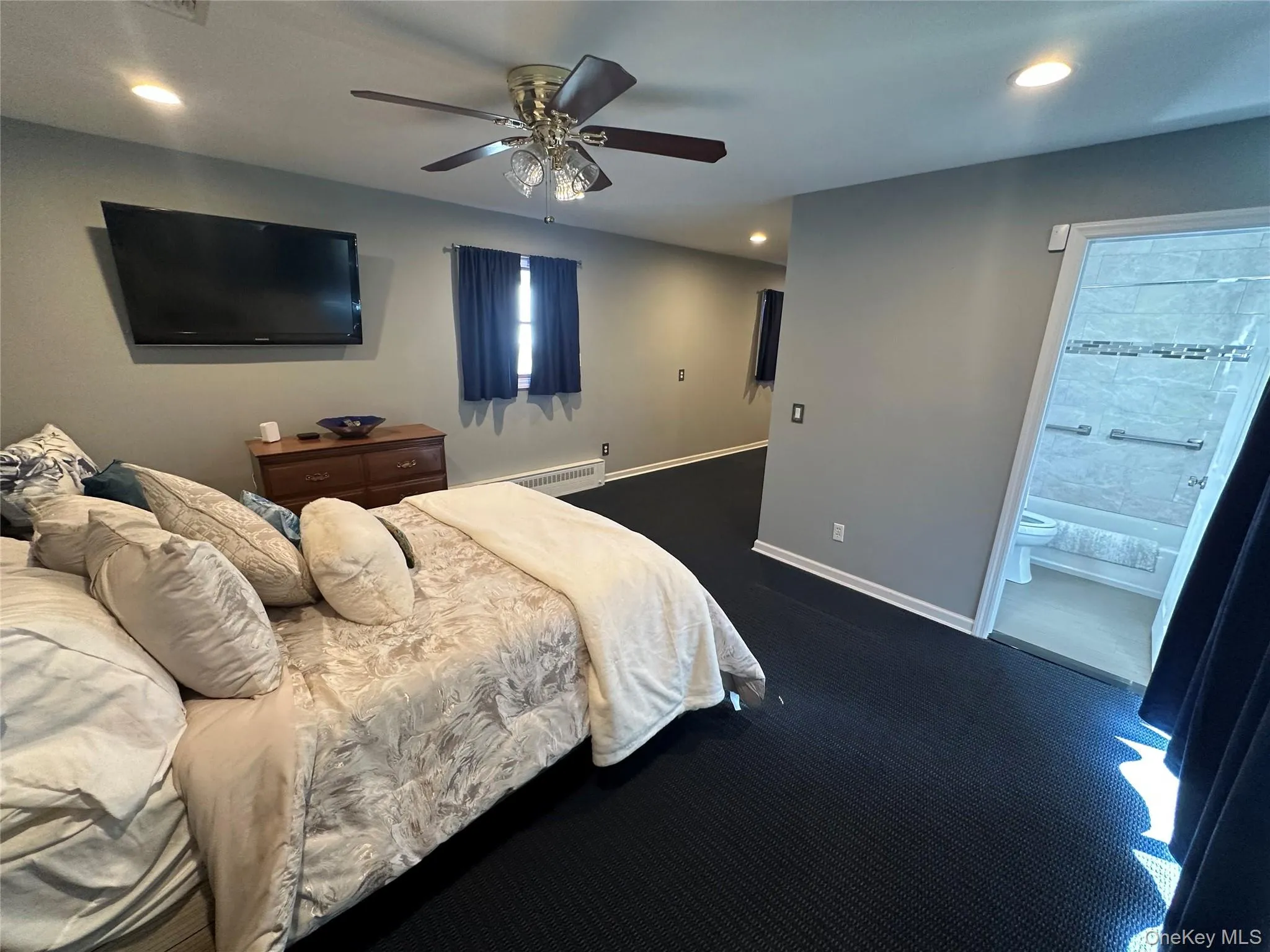Spacious interior room with neutral-toned walls, dark carpeting, recessed lighting, and a ceiling fan Spacious interior room with neutral-toned walls, dark carpeting, recessed lighting, and a ceiling fan