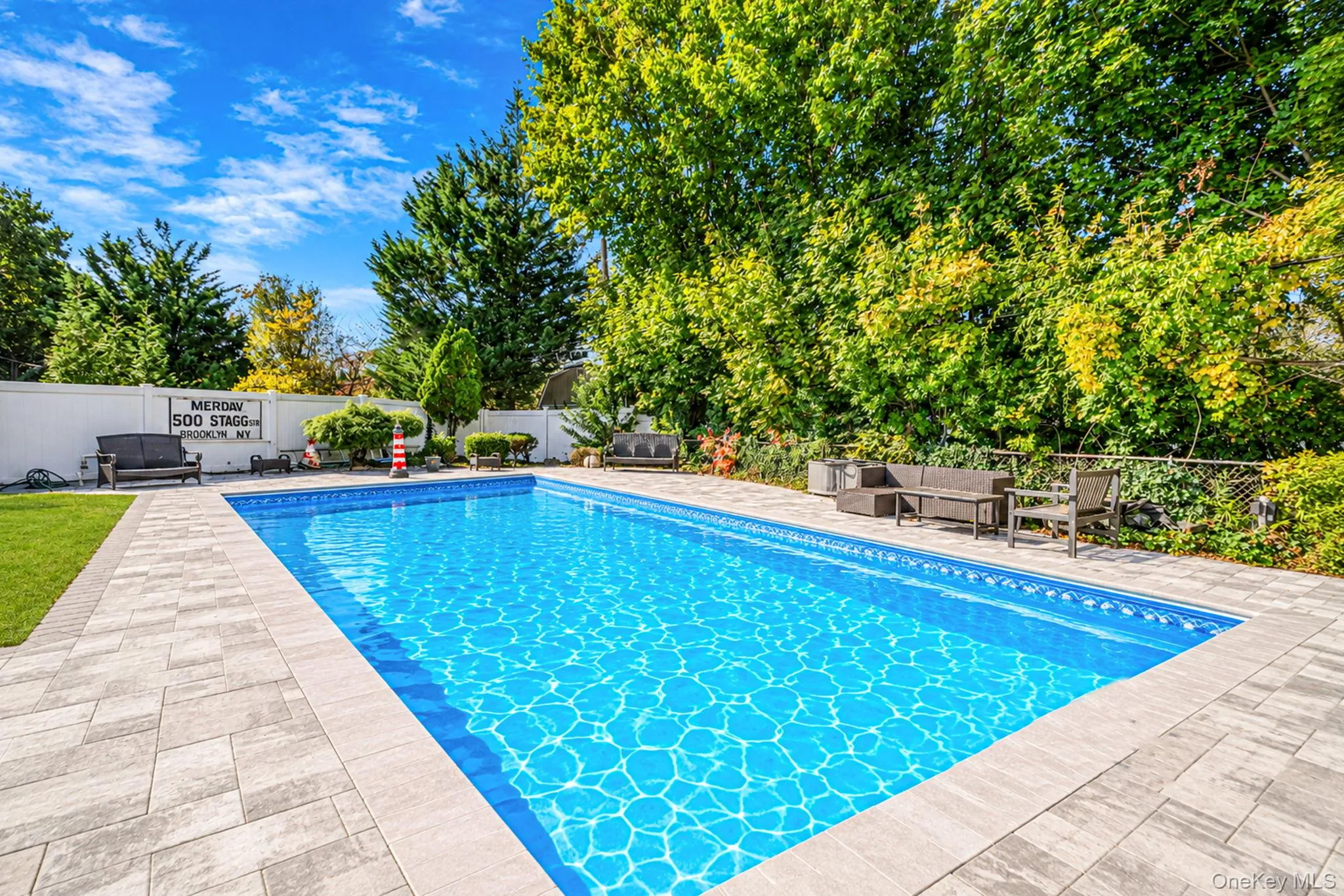 In-ground swimming pool featuring a concrete paver surround and white vinyl perimeter fencing In-ground swimming pool featuring a concrete paver surround and white vinyl perimeter fencing