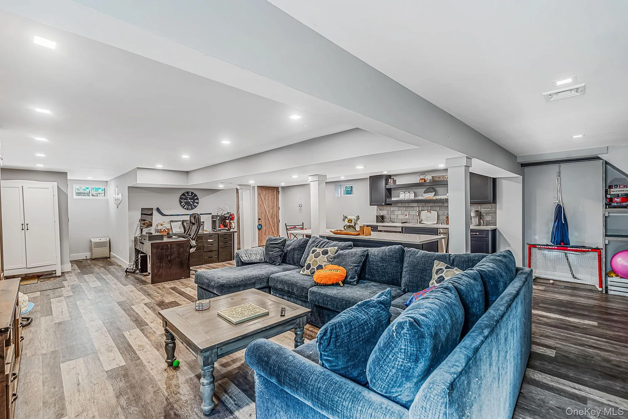 Open-concept interior featuring wood-finish flooring, recessed lighting, and a kitchenette with a central island Open-concept interior featuring wood-finish flooring, recessed lighting, and a kitchenette with a central island