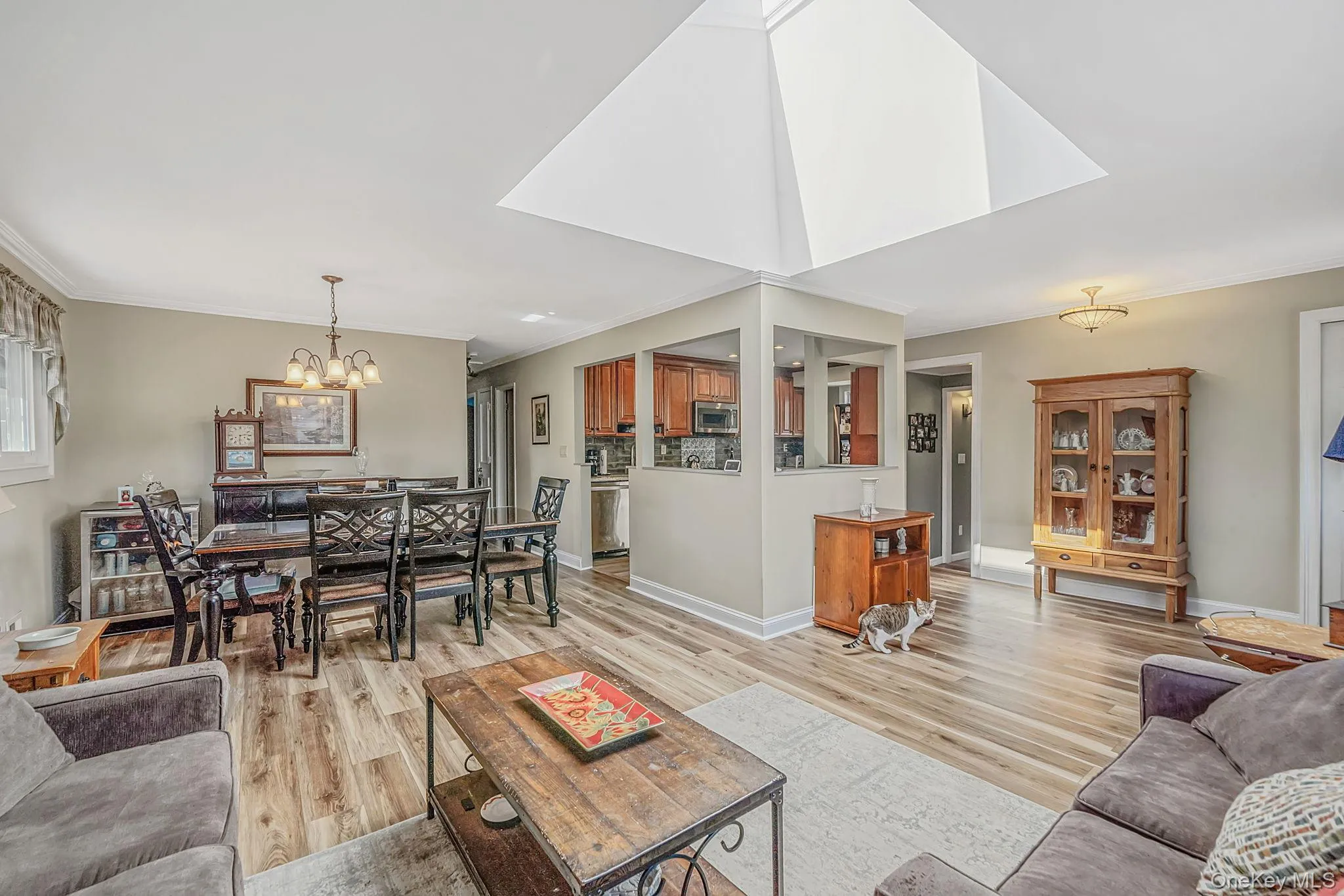 Vaulted ceiling with a large skylight, wood-finish flooring, and crown molding Vaulted ceiling with a large skylight, wood-finish flooring, and crown molding