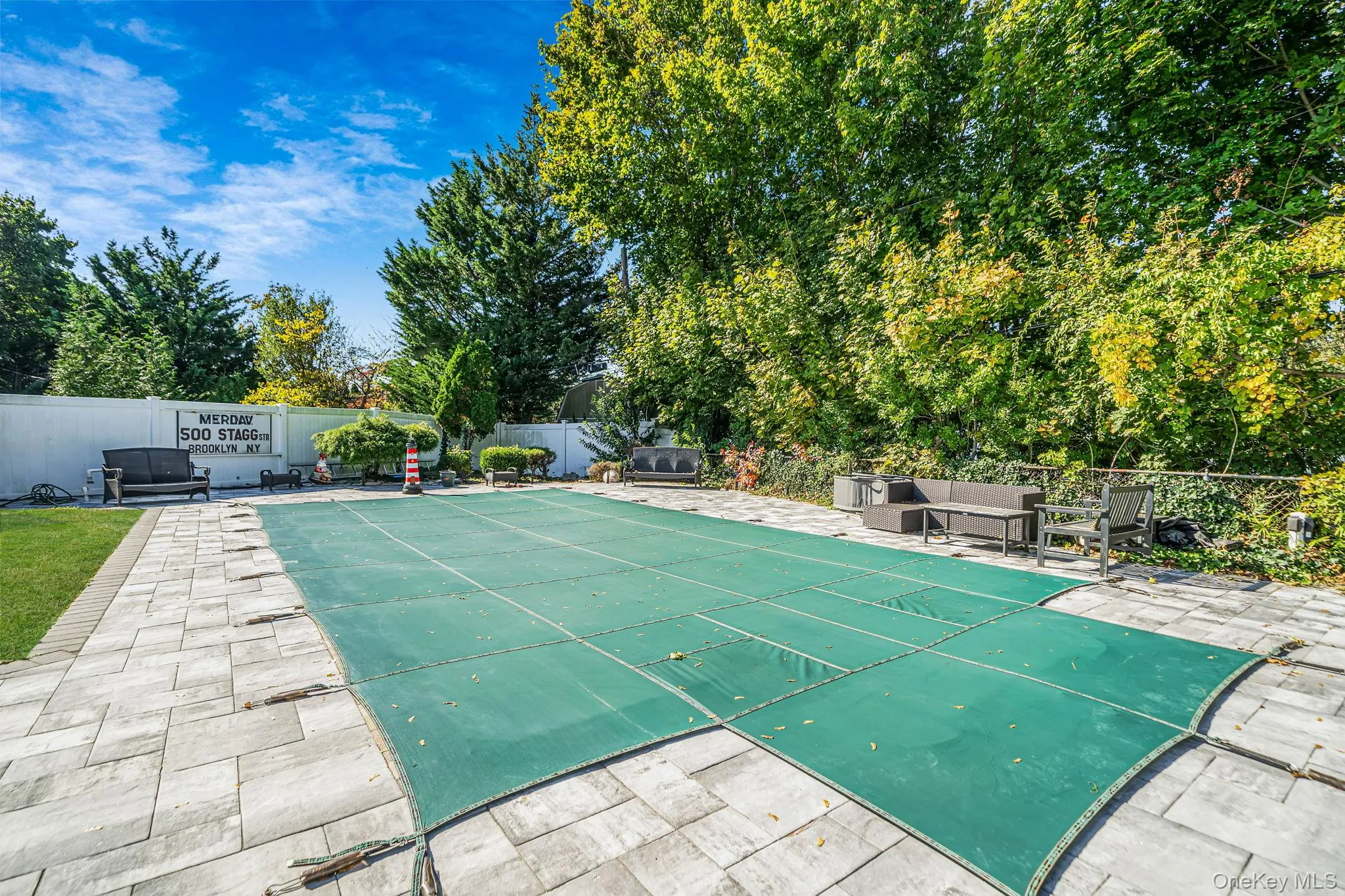 In-ground swimming pool with safety cover, surrounding stone paver patio, white vinyl privacy fencing, and mature perimeter trees In-ground swimming pool with safety cover, surrounding stone paver patio, white vinyl privacy fencing, and mature perimeter trees