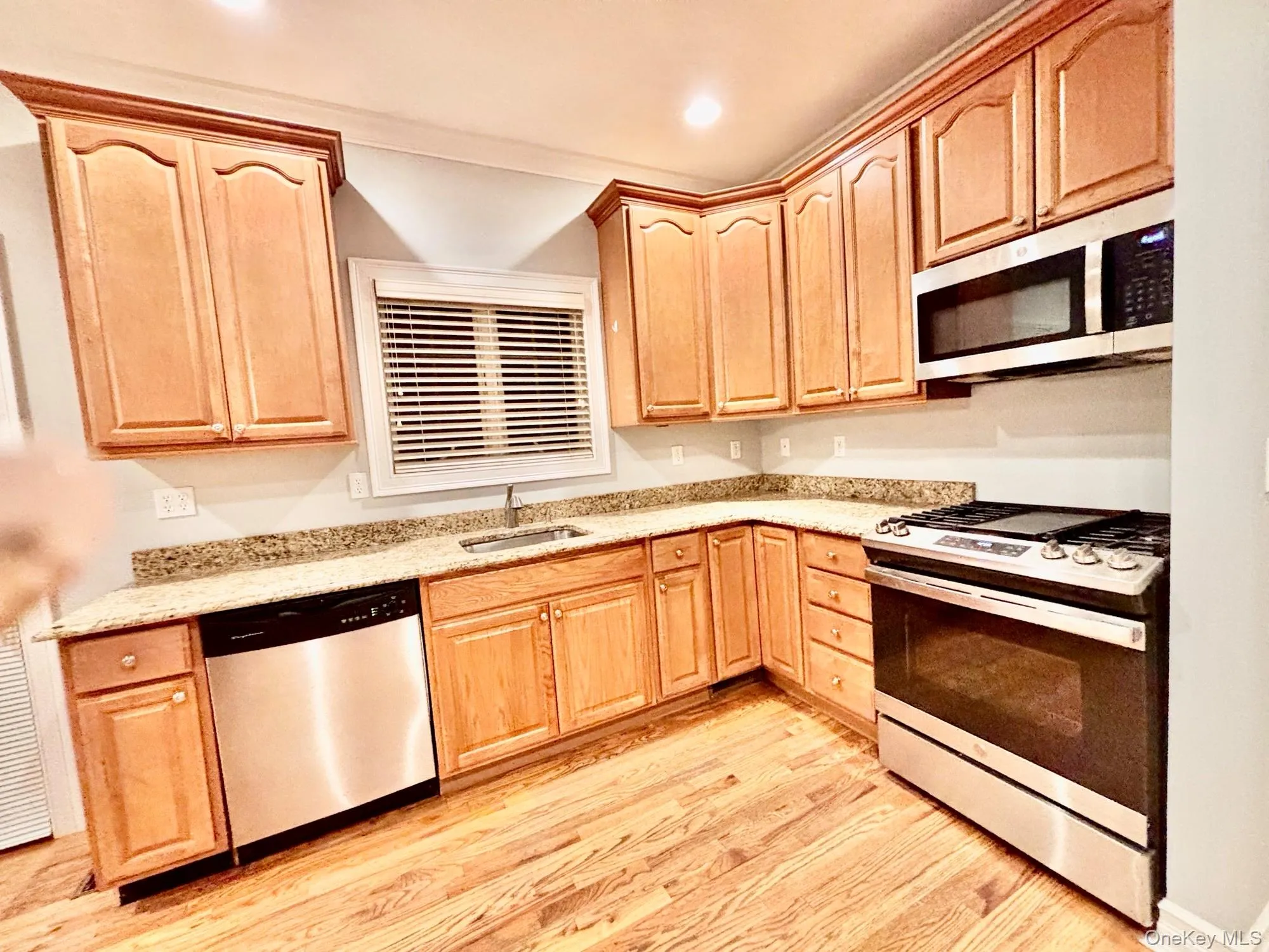 Kitchen featuring light brown cabinets, appliances with stainless steel finishes, light wood-style flooring, light stone counters, and recessed lighting Kitchen featuring light brown cabinets, appliances with stainless steel finishes, light wood-style flooring, light stone counters, and recessed lighting
