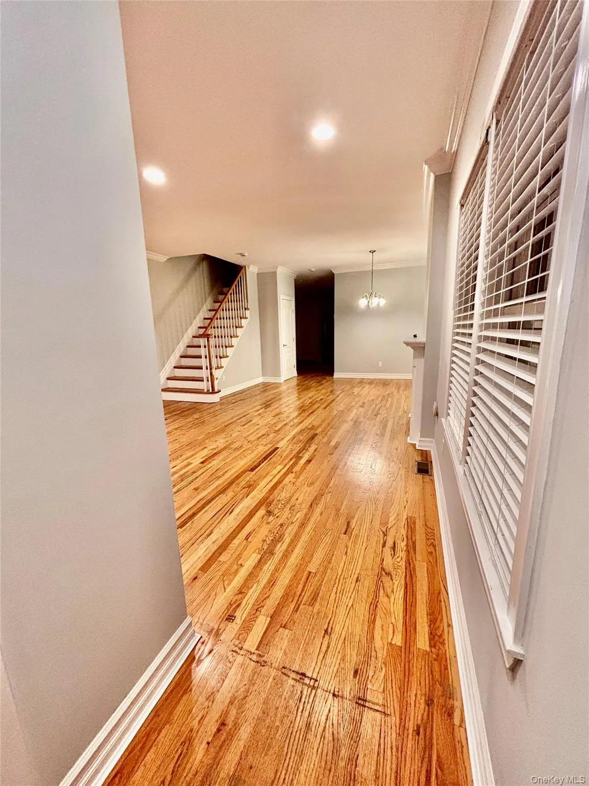 Hallway with light wood-style flooring, stairs, a chandelier, and recessed lighting Hallway with light wood-style flooring, stairs, a chandelier, and recessed lighting