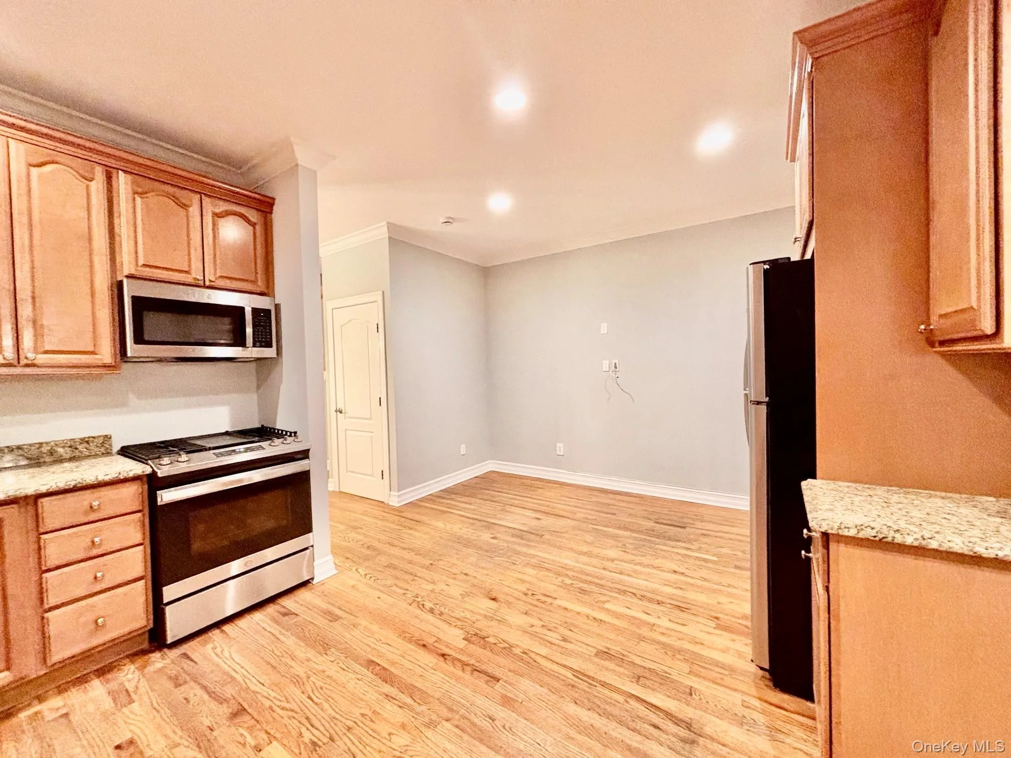 Kitchen featuring stainless steel appliances, light stone counters, light wood-type flooring, recessed lighting, and crown molding Kitchen featuring stainless steel appliances, light stone counters, light wood-type flooring, recessed lighting, and crown molding