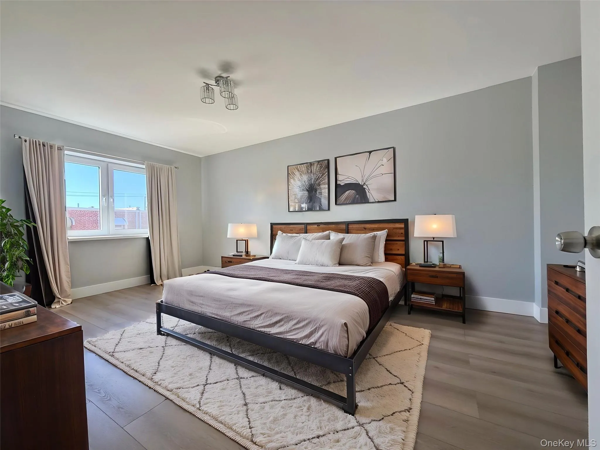 Neutral-toned walls paired with wide-plank wood-finish flooring and a multi-bulb flush-mount ceiling fixture Neutral-toned walls paired with wide-plank wood-finish flooring and a multi-bulb flush-mount ceiling fixture