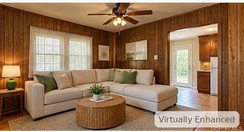 Living space featuring natural wood-finish wall paneling, multi-pane windows, and a central ceiling fan with integrated lighting Living space featuring natural wood-finish wall paneling, multi-pane windows, and a central ceiling fan with integrated lighting