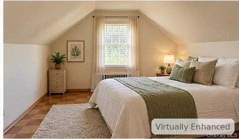 Attic-style room with vaulted ceilings, checkered parquet flooring, and a single window featuring a metal radiator cover Attic-style room with vaulted ceilings, checkered parquet flooring, and a single window featuring a metal radiator cover