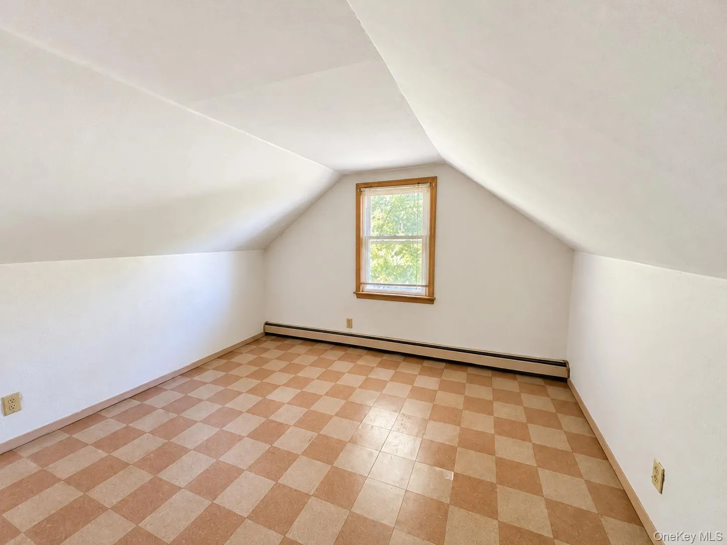 Finished attic space featuring vaulted ceilings, checkered pattern flooring, and a window with natural wood trim Finished attic space featuring vaulted ceilings, checkered pattern flooring, and a window with natural wood trim