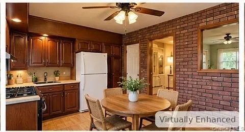 Kitchen featuring stained wood cabinetry, exposed brick wall, inset mirror, and ceiling-mounted fan with light fixture Kitchen featuring stained wood cabinetry, exposed brick wall, inset mirror, and ceiling-mounted fan with light fixture