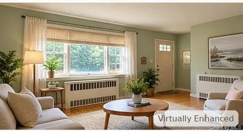 Living space featuring large multi-pane windows, wood-finish flooring, and white custom radiator covers Living space featuring large multi-pane windows, wood-finish flooring, and white custom radiator covers