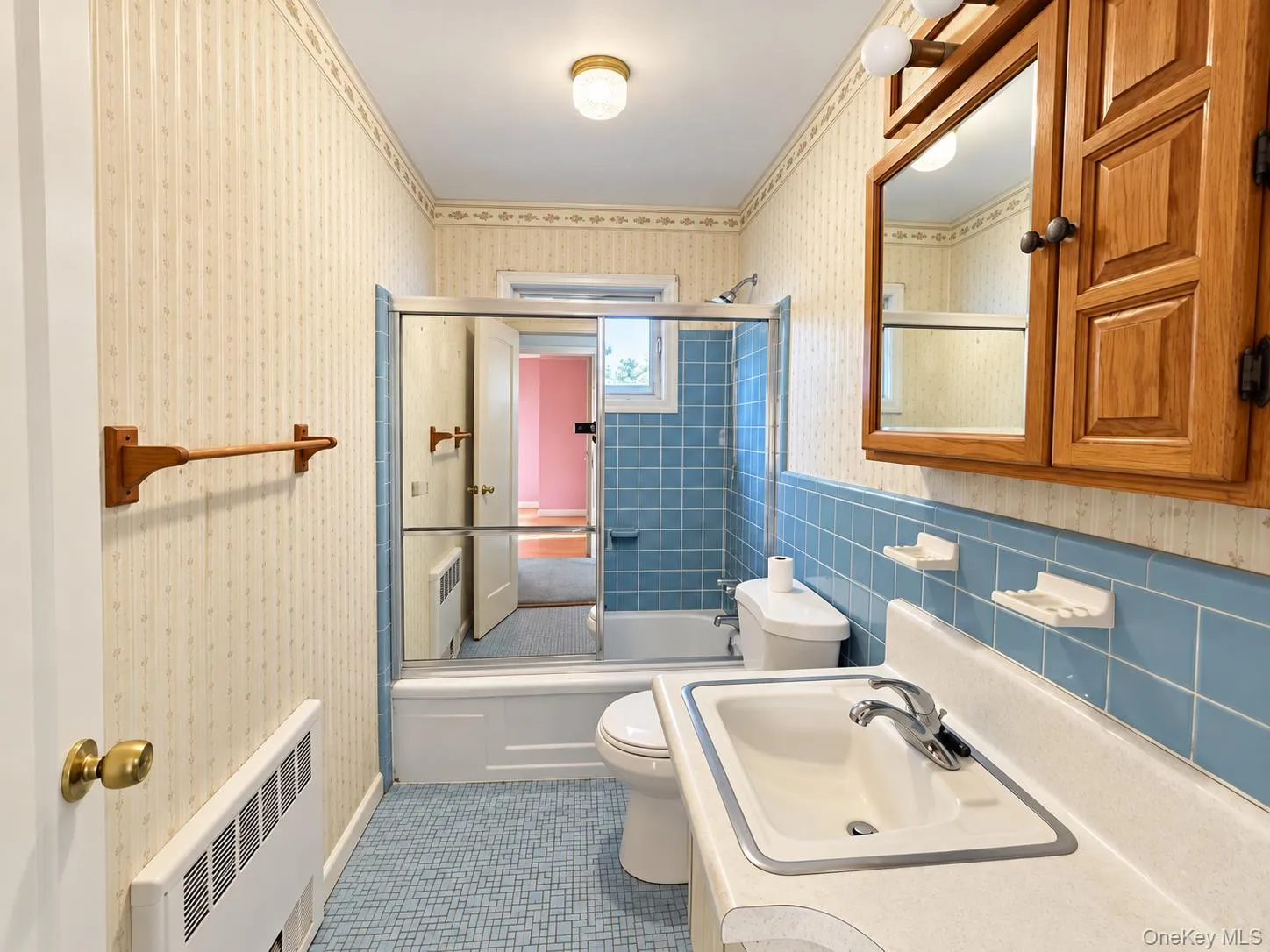 Bathroom featuring a ceramic tile shower surround, integrated sink vanity, wooden medicine cabinet, and patterned tile flooring Bathroom featuring a ceramic tile shower surround, integrated sink vanity, wooden medicine cabinet, and patterned tile flooring