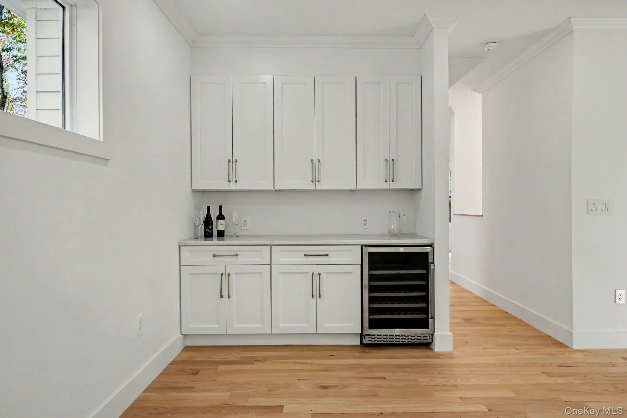 A refined butler's area featuring custom cabinetry, generous counter space, and a built-in wine refrigerator. A refined butler's area featuring custom cabinetry, generous counter space, and a built-in wine refrigerator.