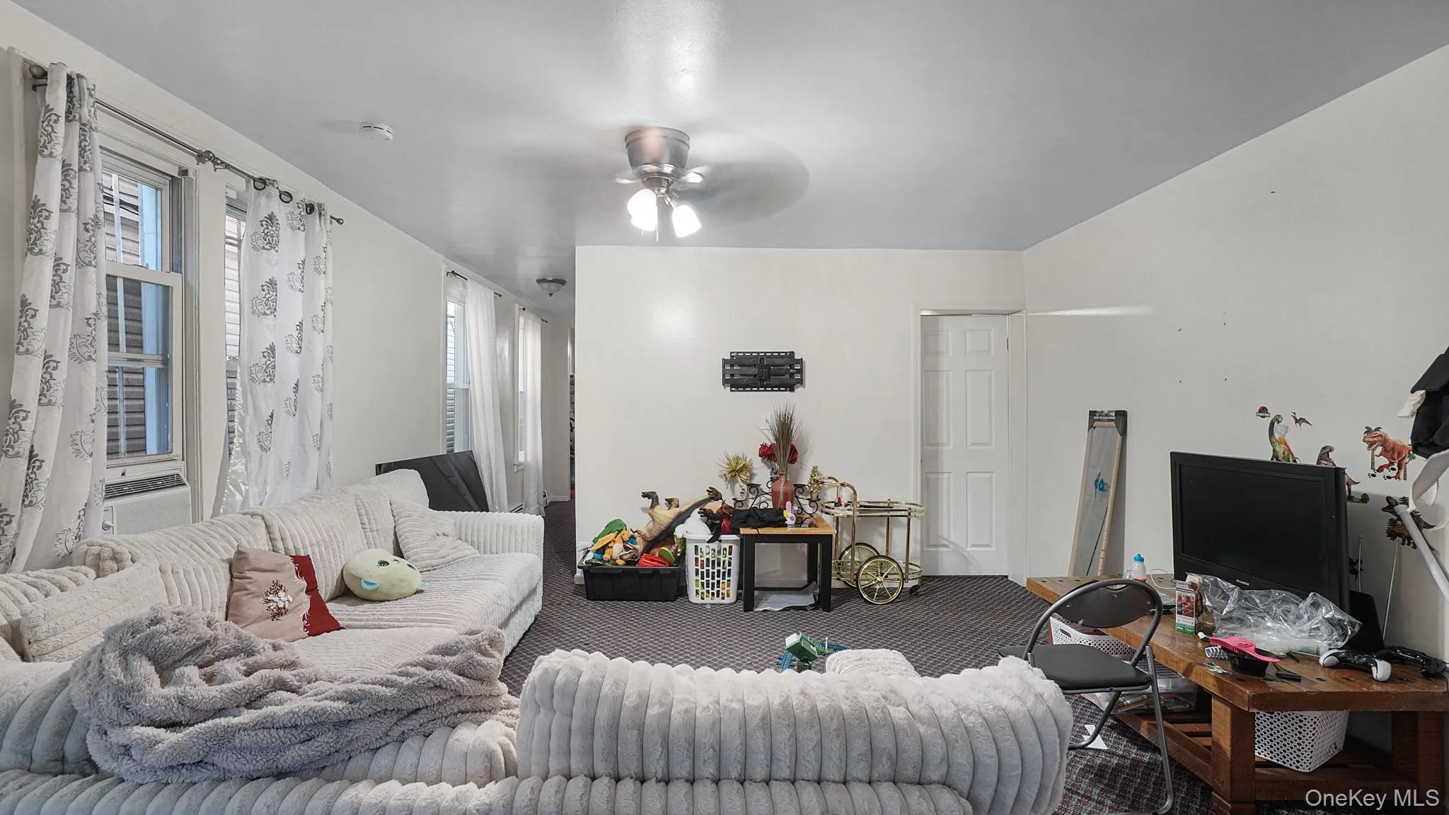 Interior space featuring multiple windows, patterned carpeting, and a ceiling-mounted light fixture with a fan Interior space featuring multiple windows, patterned carpeting, and a ceiling-mounted light fixture with a fan