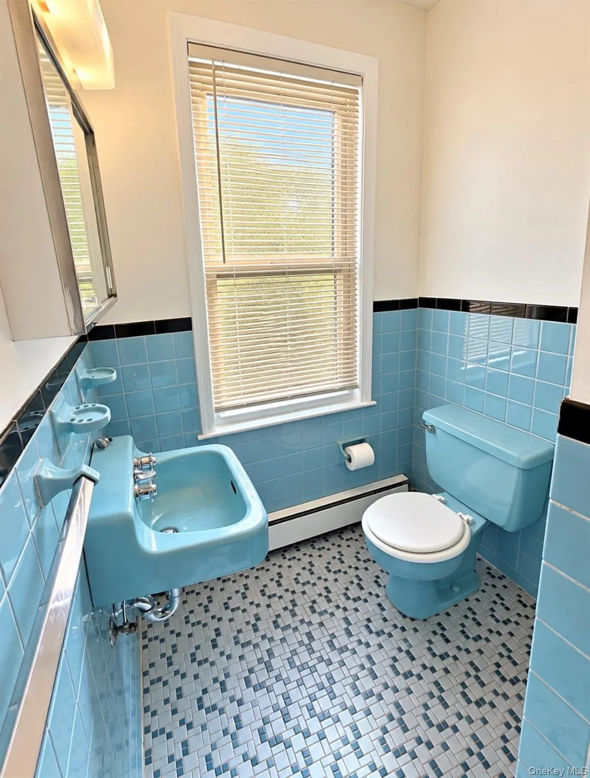 Wall-mounted ceramic sink, floor-to-ceiling tilework with black accent border, geometric mosaic tile flooring, and integrated wall-mounted soap dishes Wall-mounted ceramic sink, floor-to-ceiling tilework with black accent border, geometric mosaic tile flooring, and integrated wall-mounted soap dishes