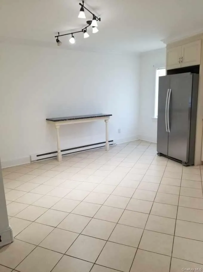 Ceramic tile flooring, stainless steel side-by-side refrigerator, built-in upper cabinetry, and adjustable multi-light track lighting Ceramic tile flooring, stainless steel side-by-side refrigerator, built-in upper cabinetry, and adjustable multi-light track lighting