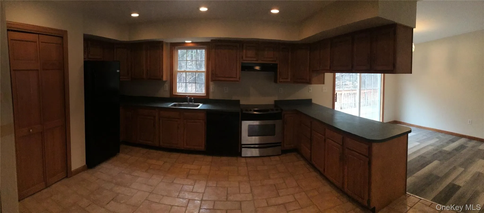 Kitchen featuring black appliances, dark countertops, recessed lighting, a peninsula, and extractor fan Kitchen featuring black appliances, dark countertops, recessed lighting, a peninsula, and extractor fan