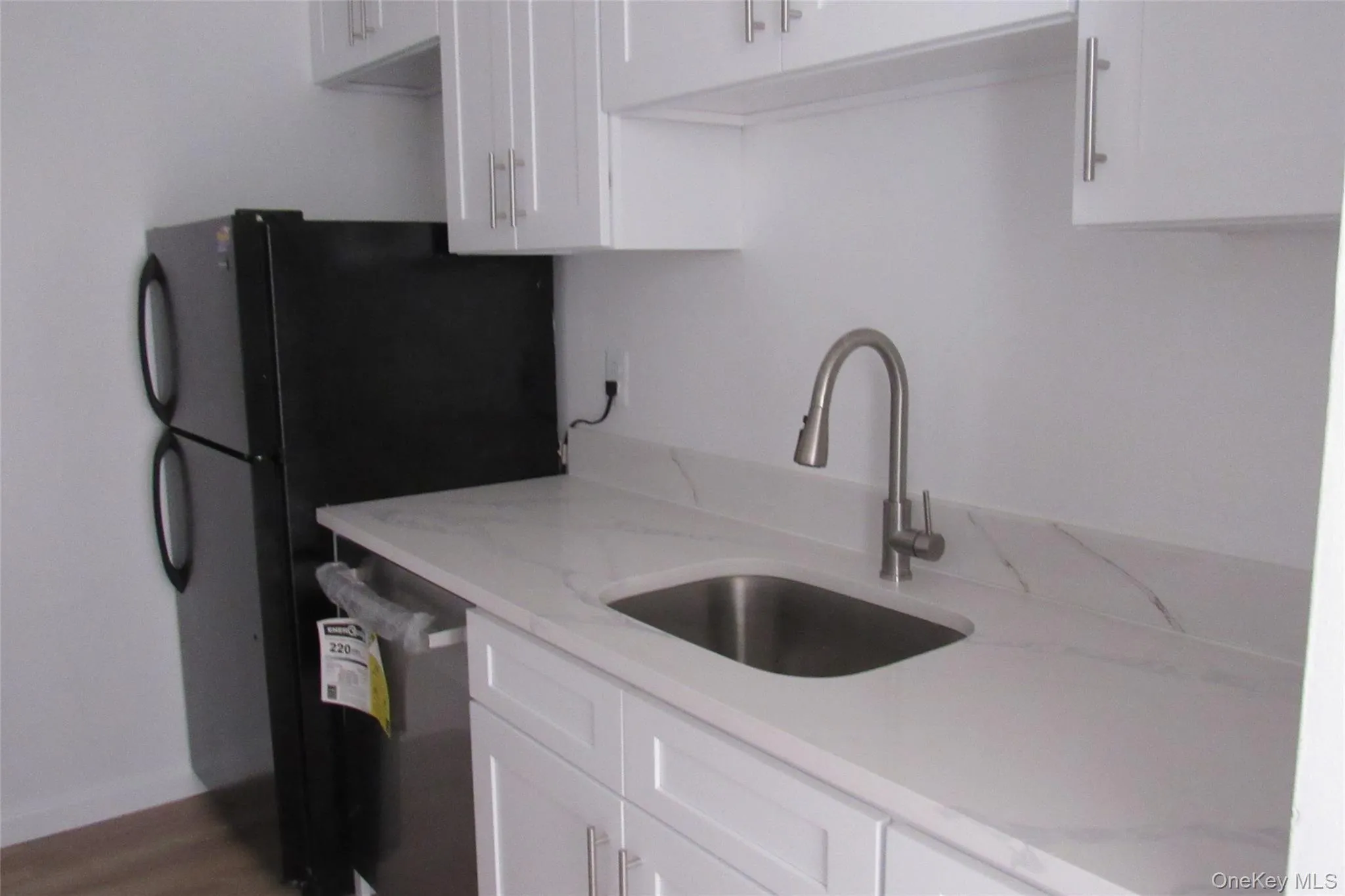White Shaker-style cabinetry featuring satin-finish hardware, quartz countertop, stainless steel undermount sink, and high-arc gooseneck faucet White Shaker-style cabinetry featuring satin-finish hardware, quartz countertop, stainless steel undermount sink, and high-arc gooseneck faucet
